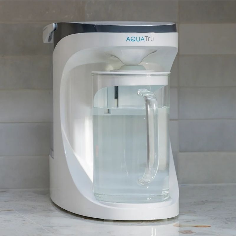 AquaTru Carafe - Glass on a marble countertop with a tiled wall background