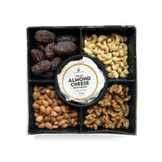 A square black gift tray divided into compartments holding almond cheese in the center surrounded by nuts and dates. The central round package reads Vegan Almond Cheese with Garlic, and the surrounding compartments show cashews, almonds, walnuts, and dark dates on a white background.

Artisanal Gluten Free Vegan Cheese & Sprouted Nuts Platter - Almond Garlic Cheese
Foodcraft Online Store
