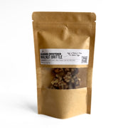 Brown paper bag with a clear window containing Banana-Sweetened Sprouted Walnut Brittles on a white background