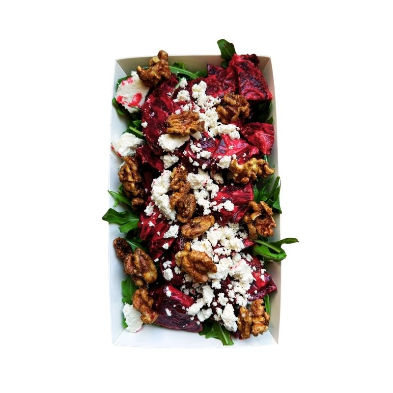 A top-down view of Beetroot Salad with Tofu Cream Cheese & Sprouted Maple Walnuts in a white rectangular paper container, featuring dark red beets, green spinach leaves, crumbled white cheese, and walnuts on a white background.