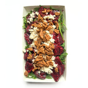 A top-down view of Beetroot Salad with Tofu Cream Cheese & Sprouted Maple Walnuts in a white rectangular paper container, featuring dark red beets, green spinach leaves, crumbled white cheese, and walnuts on a white background.