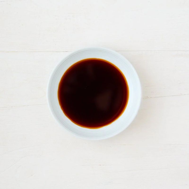 White bowl filled with Clearspring Organic Japanese Shoyu Soya Sauce on a light wooden surface