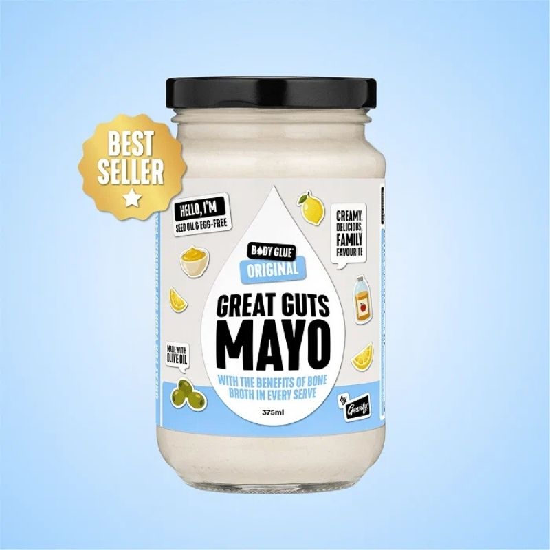 A jar of Gevity Body Glue Original Great Guts Mayo - 375ml on a light blue gradient background, featuring a black lid, cream-colored mayonnaise inside, and a white and blue label with illustrations of lemons and olives. A gold 'BEST SELLER' badge is on the left.