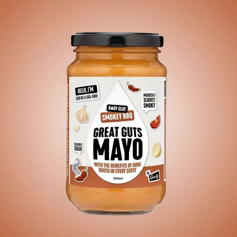 A glass jar of Gevity Body Glue Smoky BBQ Great Guts Mayo - 375ml, featuring a black lid and a white label with brown and black text, set against a solid peach-colored background.