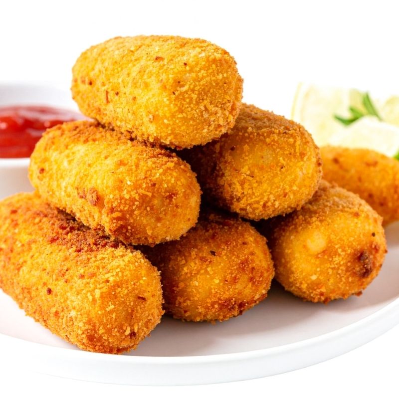 Stack of golden-brown croquettes with Gluten-Free Rice Panko Breadcrumbs on a white plate with a side of ketchup and salad.