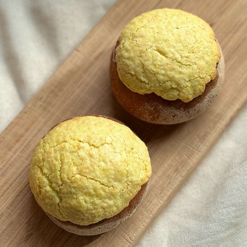 Two Gluten Free Vegan Sourdough Pineapple Buns on a wooden board with a neutral background