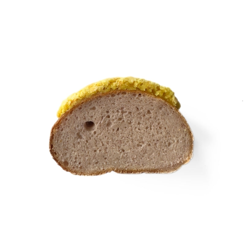 Half of a Gluten Free Vegan Sourdough Pineapple Bun with a yellow crust on a white background