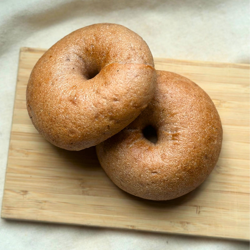 Two Gluten-Free Soft Original Sourdough  bagels resting on a rectangular wooden board against a light fabric background.
Gluten-Free Soft Original Sourdough Bagel - Set of 2 - FoodCraft Online Store 