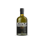 A bottle of ILIADA Early Harvest Extra Virgin Olive Oil Unfiltered - 500ml against a plain white background. The bottle is made of dark glass showing the golden-amber liquid inside, with a black label featuring bold white text and a black cap.