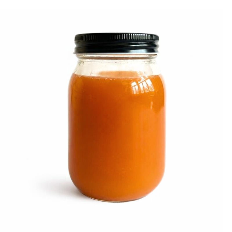 An orange-reddish liquid- Italian Red Fleshed Apple & Cinnamon Water Kefir - 400ml (Foodcraft Online Store) filled in a clear glass mason jar with a black metal screw cap, set against a plain white background.