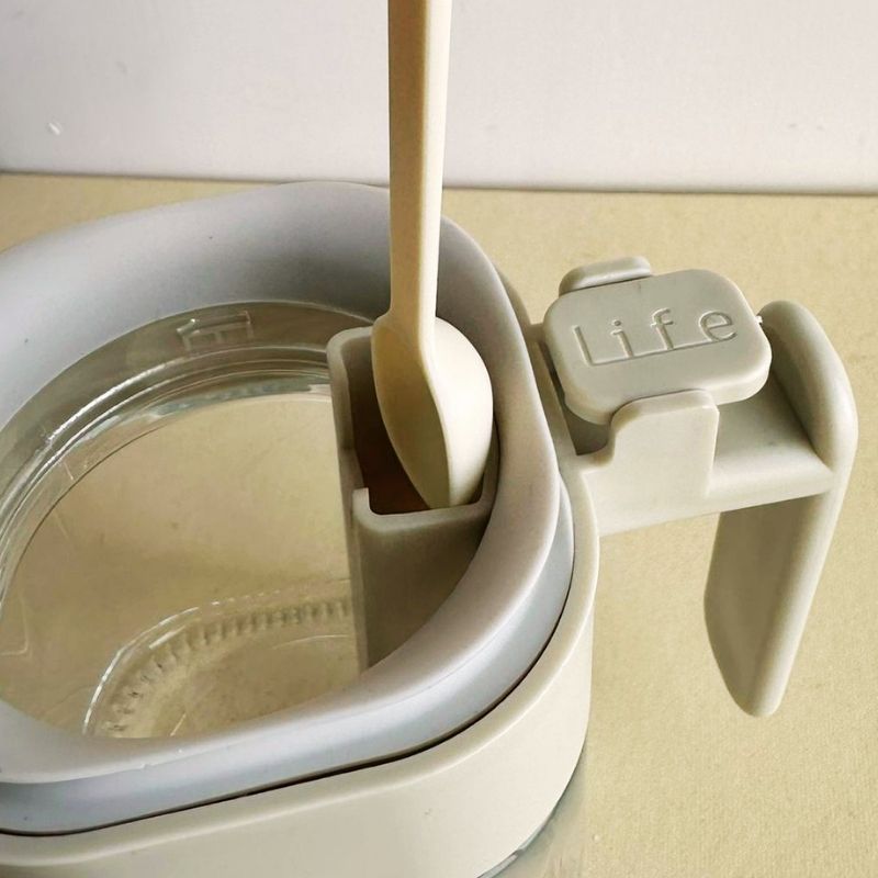 A close up photo of Japanese-Style Airtight Condiment Glass Pot - 300ml with a lid and handle on a beige background