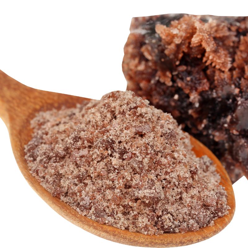 Wooden spoon filled with Kala Namak (Himalayan Black Salt) next to a rock salt on a white background