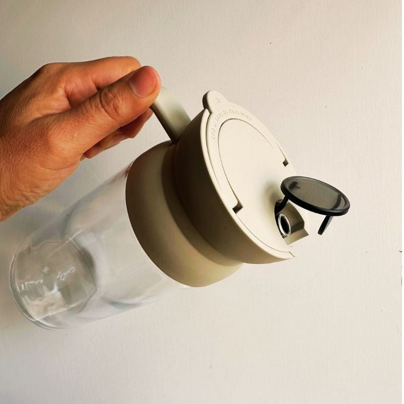 Hand holding Leak-Proof Glass Oil Dispenser / Liquid Condiment Bottle - 600ml on a white background.
