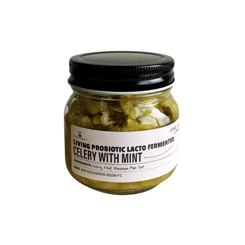 Jar of living probiotic lacto fermented celery with mint on a white background