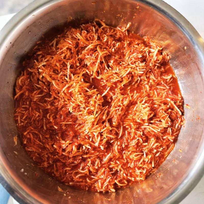 Metal bowl filled with Living Lacto-Fermented Kimchee Daikon on a white background