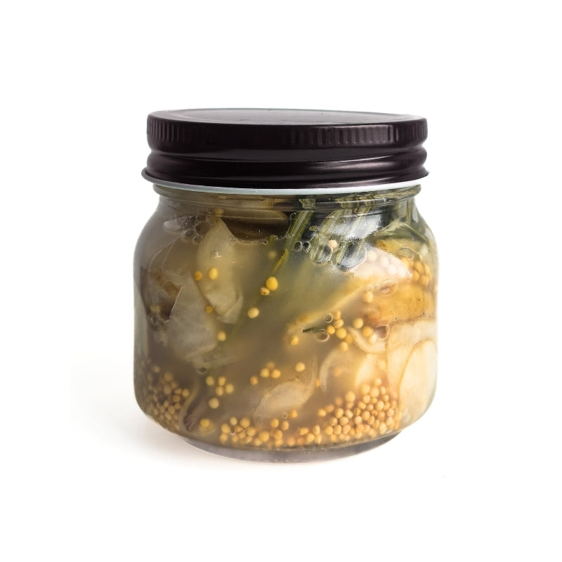Glass jar with black lid containing Living Lacto-Fermented Sunchoke with Rosemary on a white background