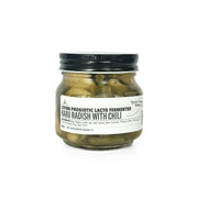 Jar of Living Lacto-Fermented Kabu Radish with Chili with a black lid on a white background