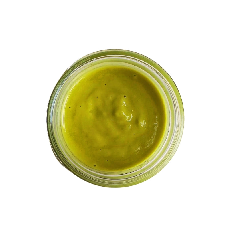 A top-down view of a small clear glass jar filled with thick Living Probiotic Creamy Jalapeno Sauce - 200g, centered on a plain white background.
