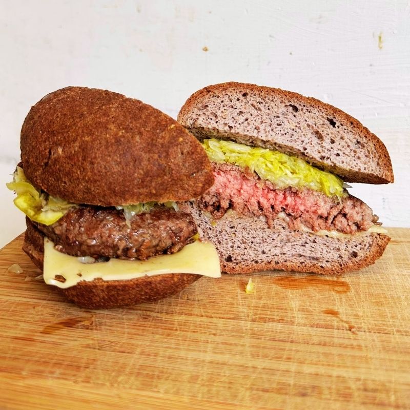 Low Carb Keto Buns Hamburger cut in half on a wooden cutting board with a white background