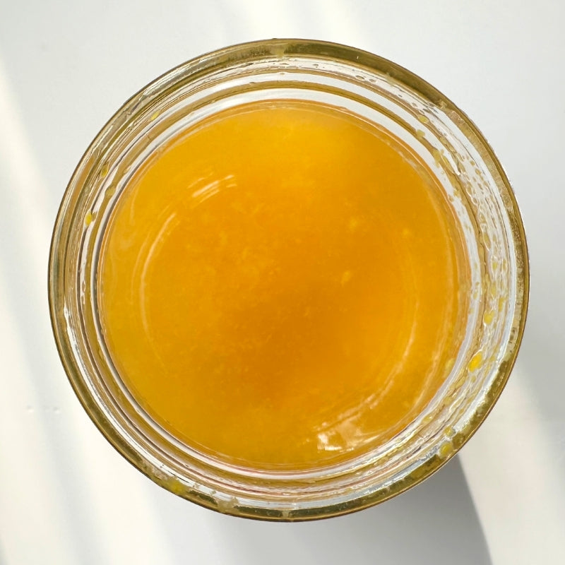 Top-down view of a clear glass jar filled with  bright golden yellow Mango Coconut Water Kefir - 400ml
Foodcraft Online Store set against a clean white background.
