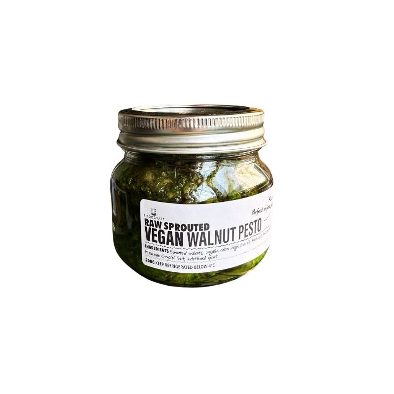 A glass jar of Raw Sprouted Vegan Walnut Pesto - 200g with a silver metal lid and a white label, set against a plain white background.