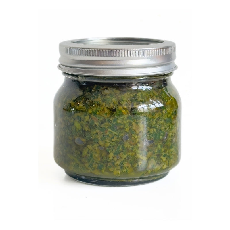 Glass jar with Raw Sprouted Walnut Pesto and silver lid on a white background