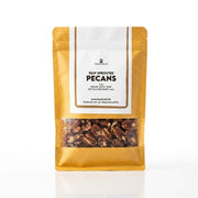 A stand-up pouch of Foodcraft Raw Sprouted Pecans on a clean white background. The packaging is made with kraft paper with a white label and a clear window at the bottom showing the brown pecans inside.