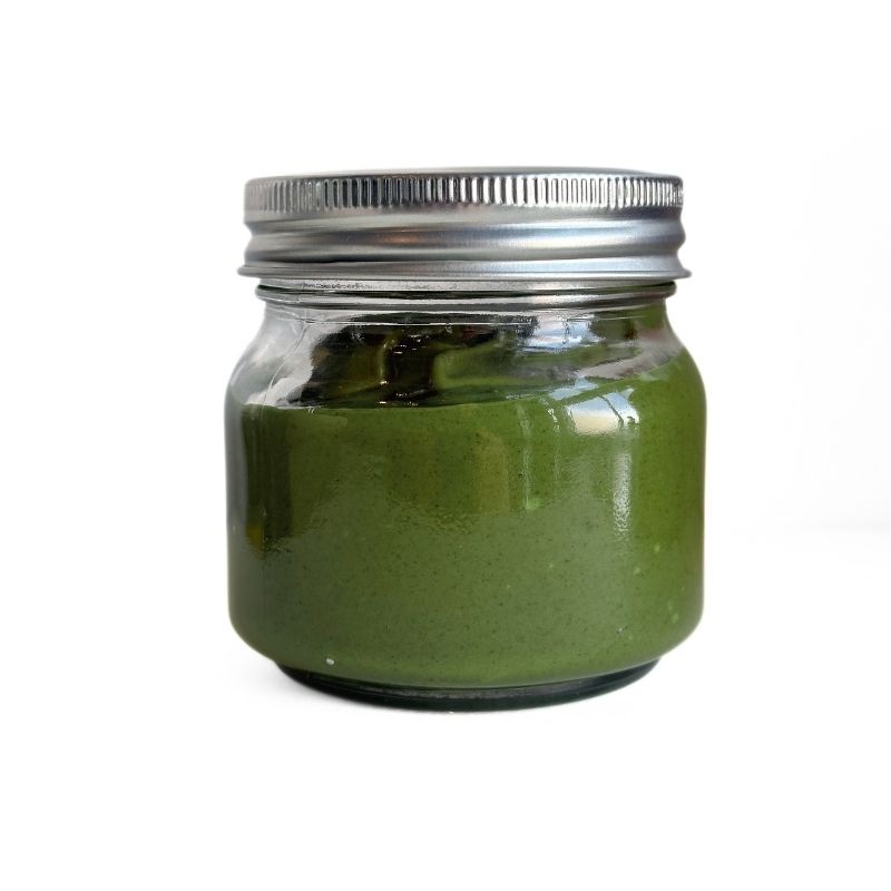 Glass jar with Raw Sprouted Pumpkin Seed Butter  and silver lid on a white background