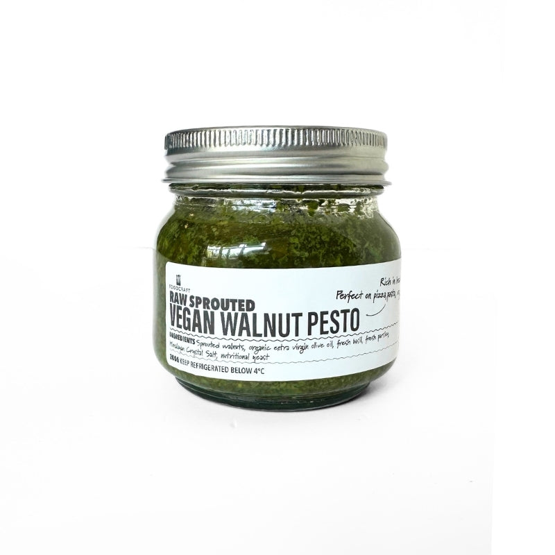 A glass jar of Raw Sprouted Vegan Walnut Pesto - 200g with a silver metal lid and a white label, set against a plain white background.