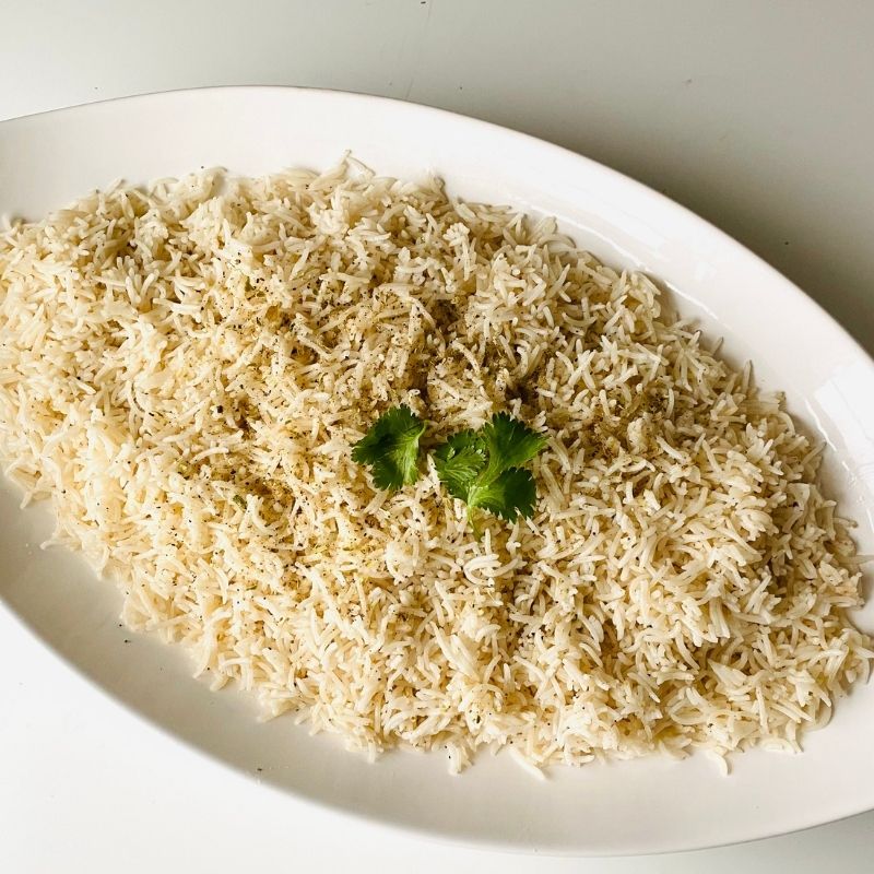 Platter of Spice Box Organic Brown Basmati Rice with a sprig of cilantro on a white background