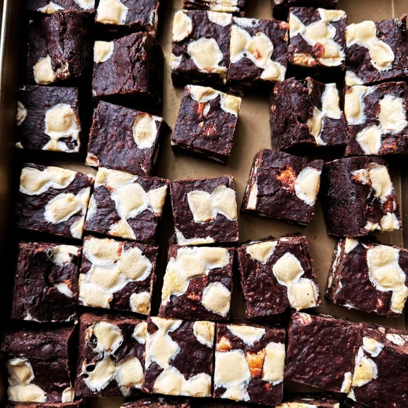 Square pieces of Vegan Gluten-Free Winter Brownie with white marshmallows on a baking sheet